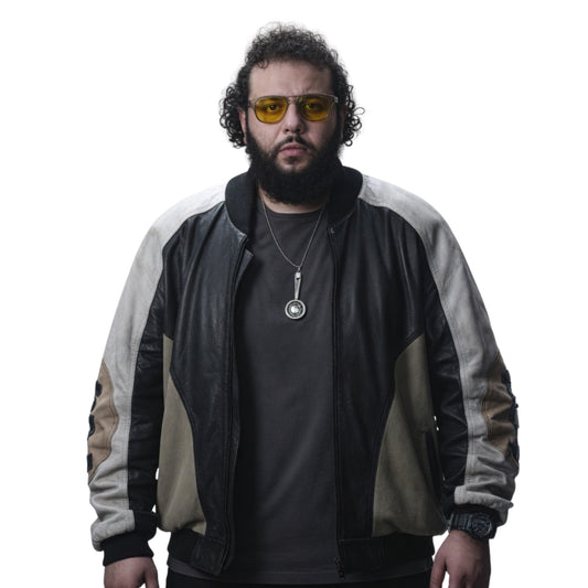 Man wearing a black and beige jacket with yellow sunglasses on a white background