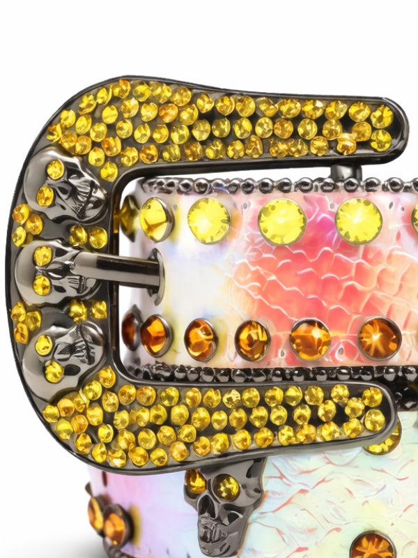 Decorative belt buckle with yellow gemstones and skull designs on a white background