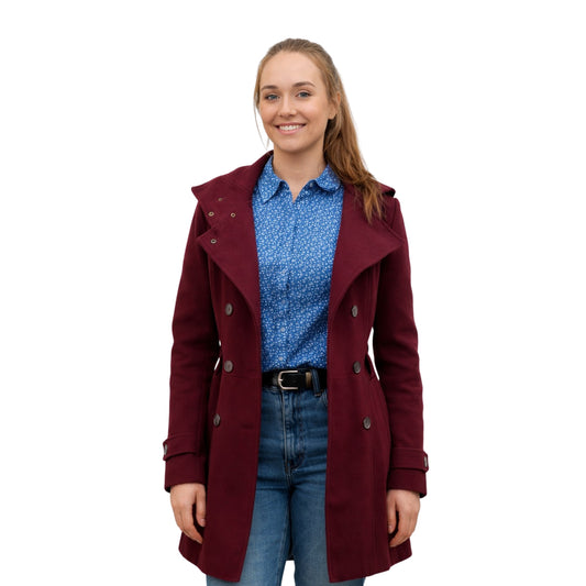 Woman wearing a burgundy coat over a blue shirt and jeans on a white background