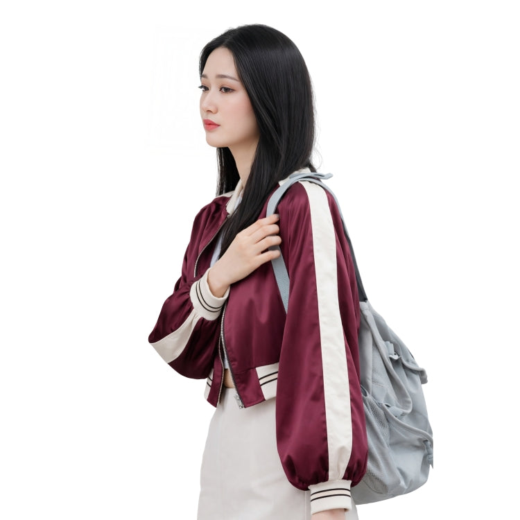 Woman wearing a maroon and white jacket with a gray backpack on a white background