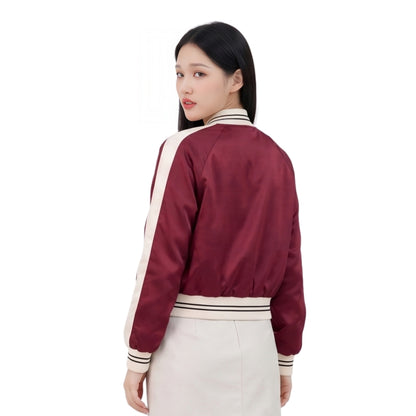 Woman wearing a maroon bomber jacket with white accents on a white background