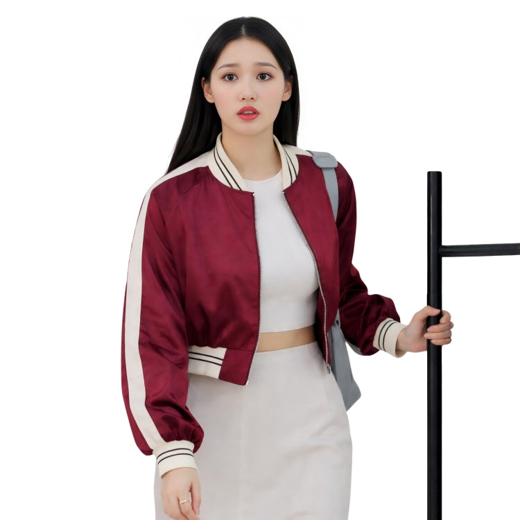 Woman wearing a red and white jacket holding a black object on a white background