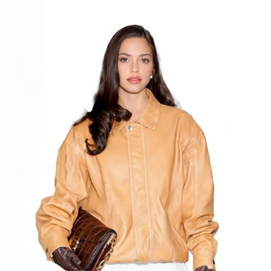 Woman wearing a tan leather jacket holding brown shoes on a white background