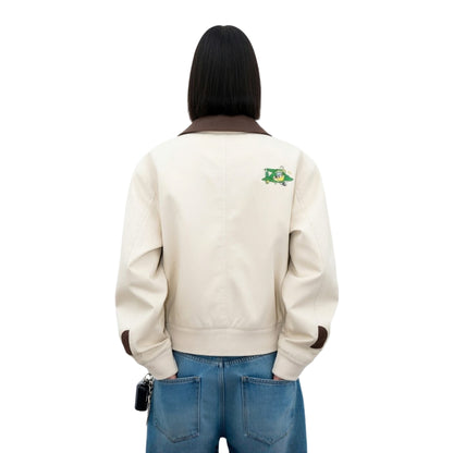 Person wearing a beige jacket with a logo on the back against a white background