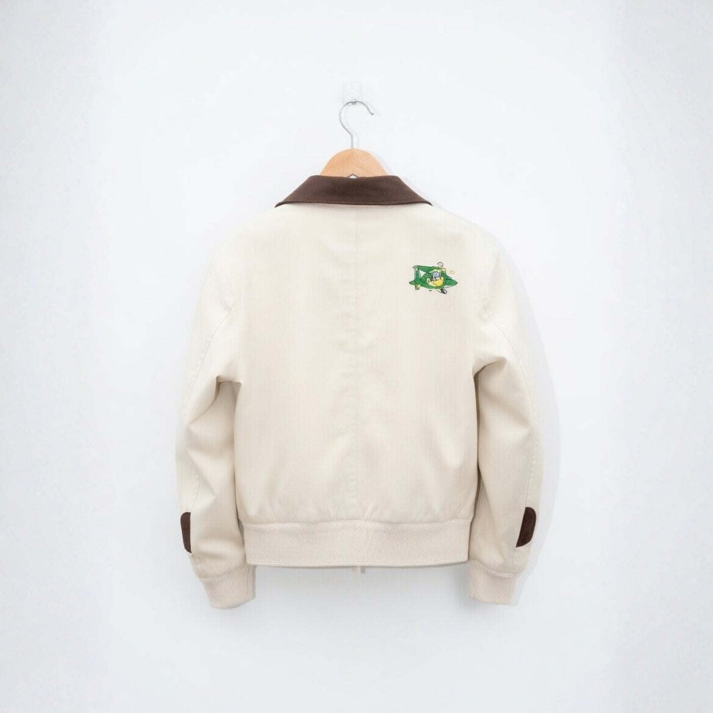 Beige jacket with brown accents on a hanger against a white background