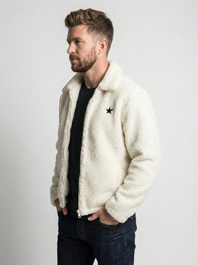 Man wearing a white sherpa jacket with a star design on a plain background