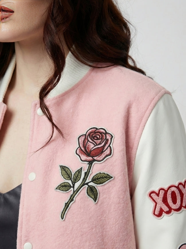 Person wearing a pink varsity jacket with a rose patch and white sleeves with red text.