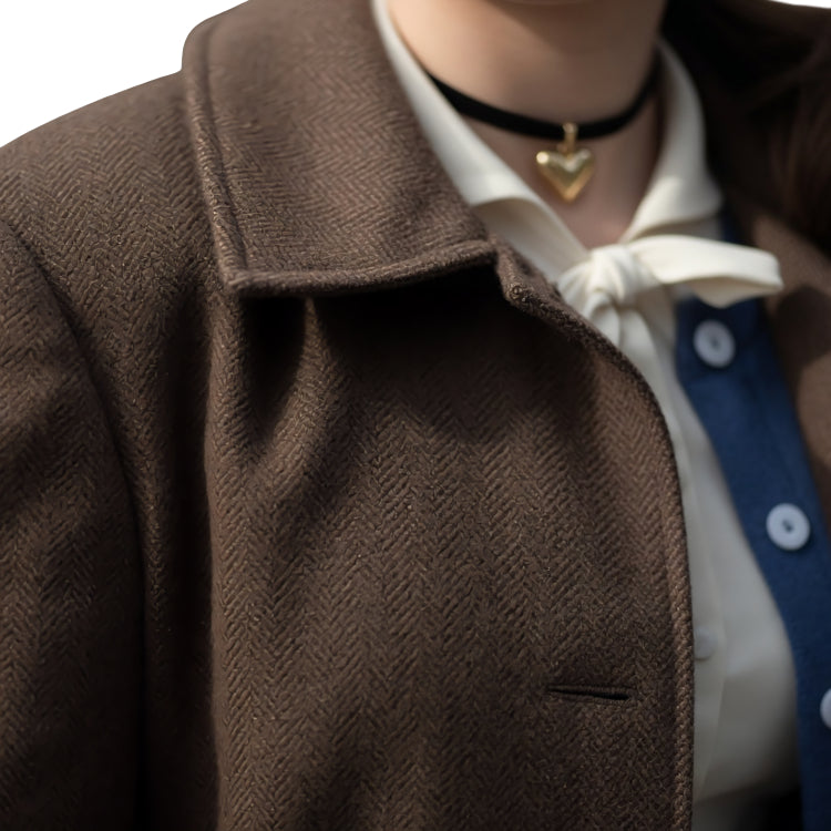 Close-up of a person wearing a brown coat with a white shirt and blue tie.