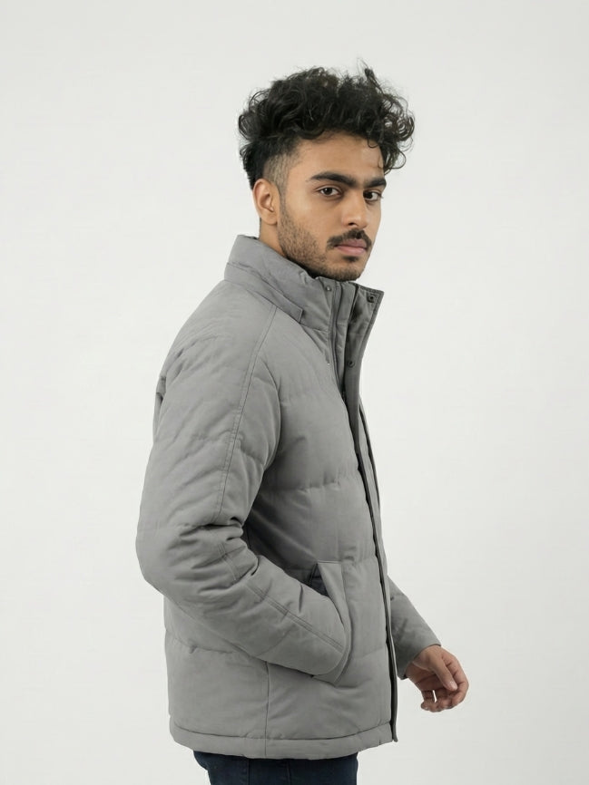 Man wearing a gray quilted jacket on a white background