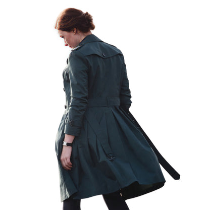 Woman wearing a dark green trench coat on a white background
