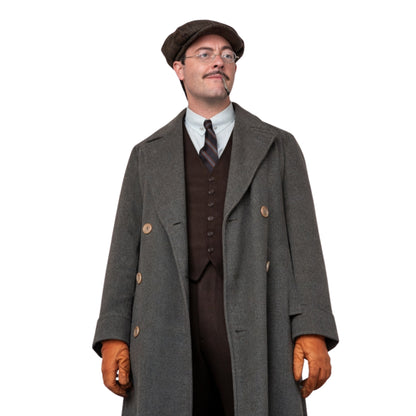 Man wearing a vintage outfit with a long coat, vest, tie, and gloves on a white background