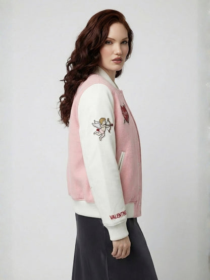Woman wearing a pink and white varsity jacket with designs on a plain background