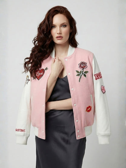 Woman wearing a pink and white varsity jacket with embroidered designs on a plain background