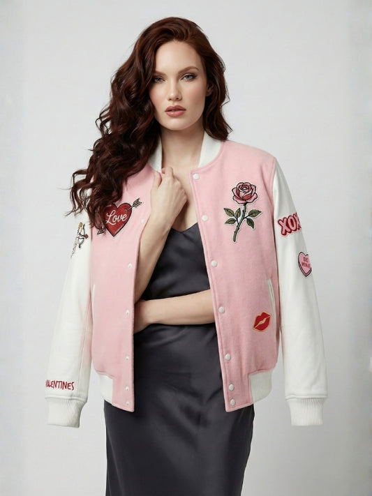 Woman wearing a pink and white varsity jacket with embroidered designs on a plain background