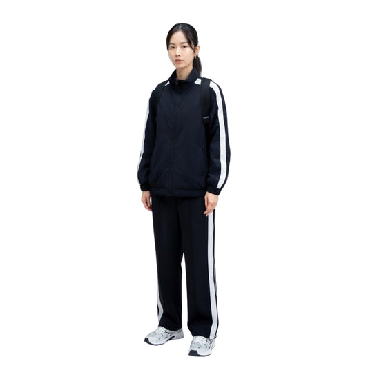 Person wearing a black tracksuit with white stripes on a white background