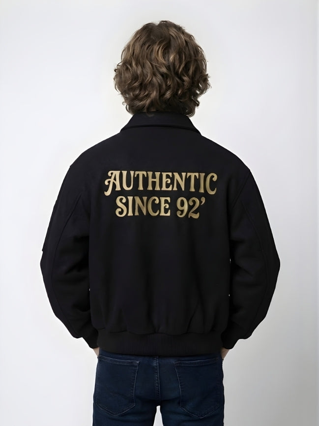 Person wearing a black jacket with 'AUTHENTIC SINCE 92' text on the back against a white background