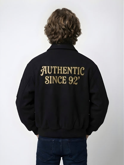 Person wearing a black jacket with 'AUTHENTIC SINCE 92' text on the back against a white background