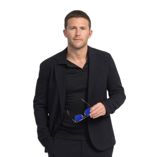 Man wearing a black suit holding blue sunglasses on a white background