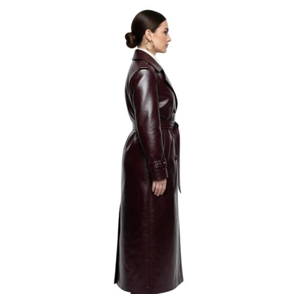 Woman wearing a long brown leather coat on a white background