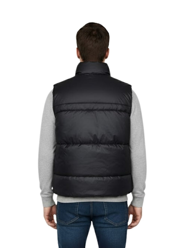 Person wearing a black puffer vest on a white background