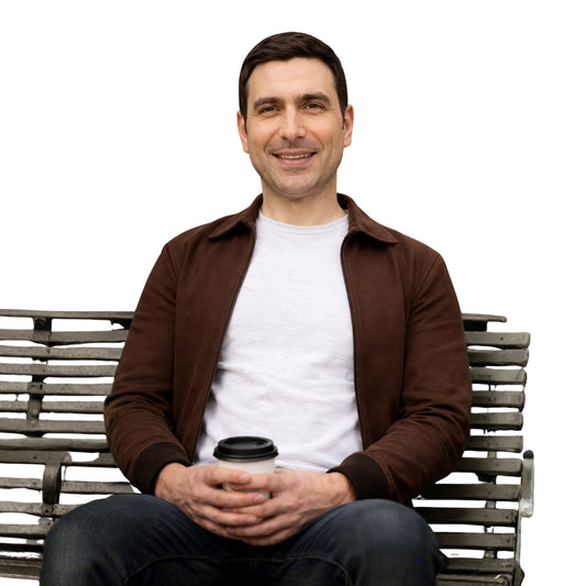 Man sitting on a bench holding a coffee cup against a white background
