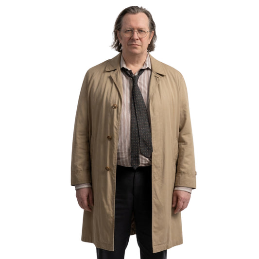 Man wearing a beige trench coat over a suit on a white background
