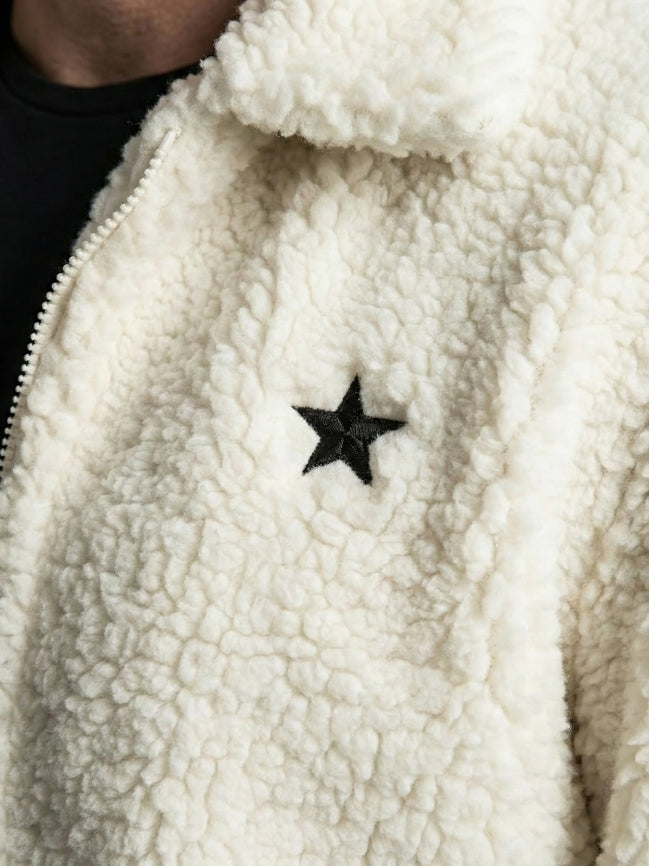 Close-up of a white fleece jacket with a black star patch.