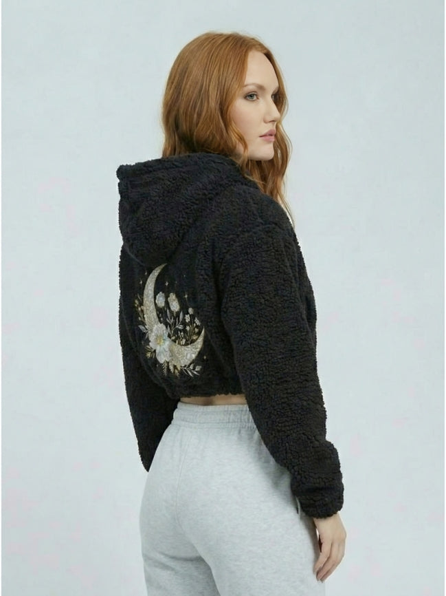 Woman wearing a black hoodie with a decorative back design on a light gray background