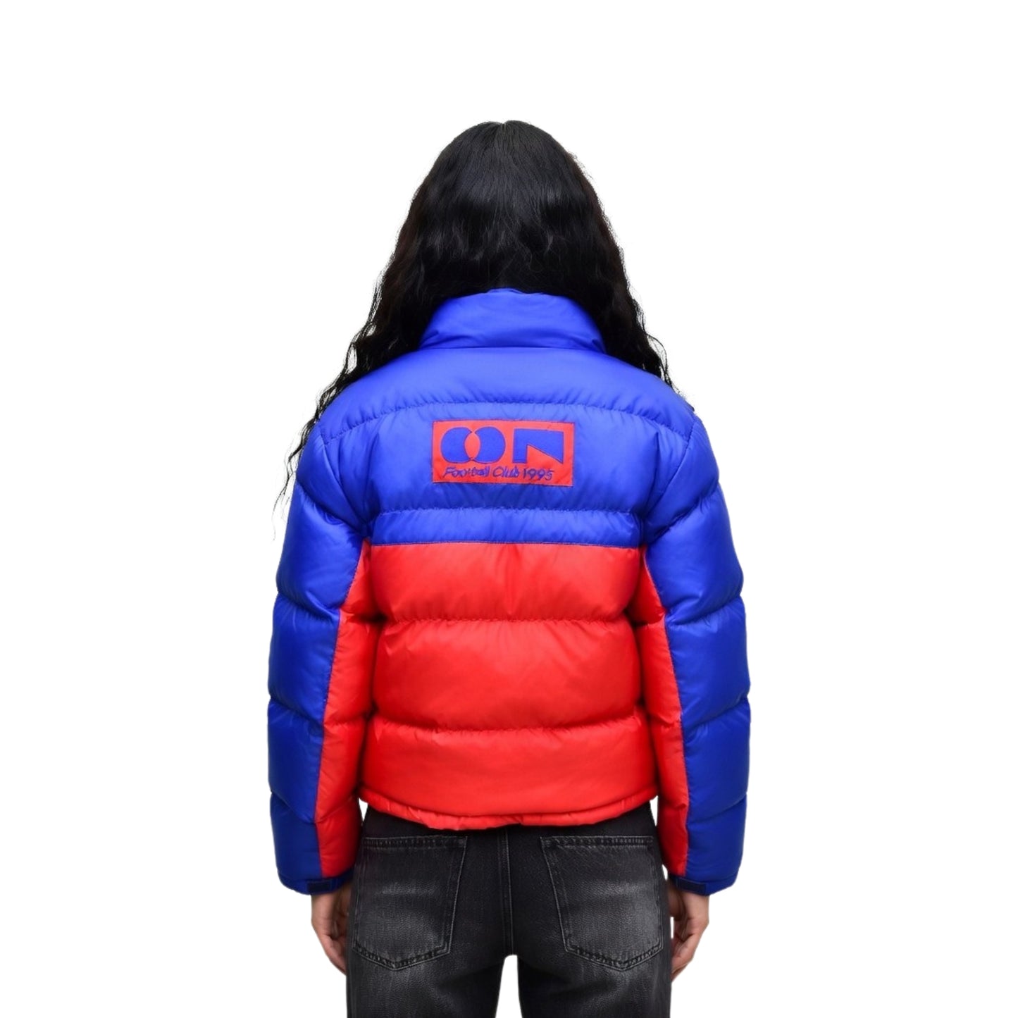 Person wearing a blue and red puffer jacket with a logo on the back against a white background