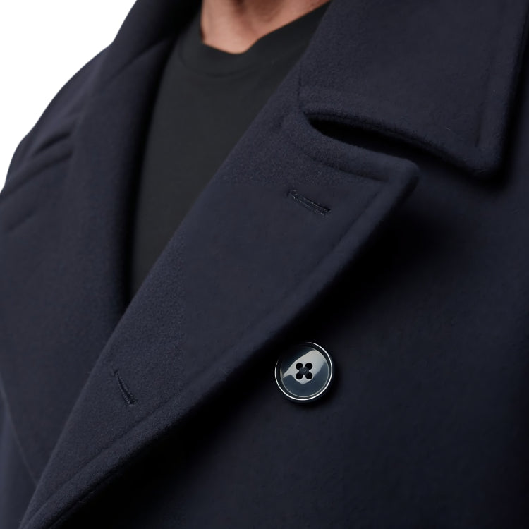 Close-up of a dark blue coat with a button, on a white background