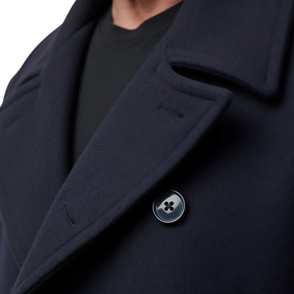 Close-up of a dark blue coat with a button, on a white background
