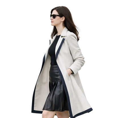 Woman wearing a long beige coat with black trim on a white background