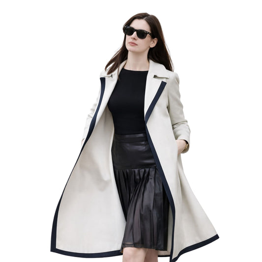 Woman wearing a long white coat with black trim on a white background