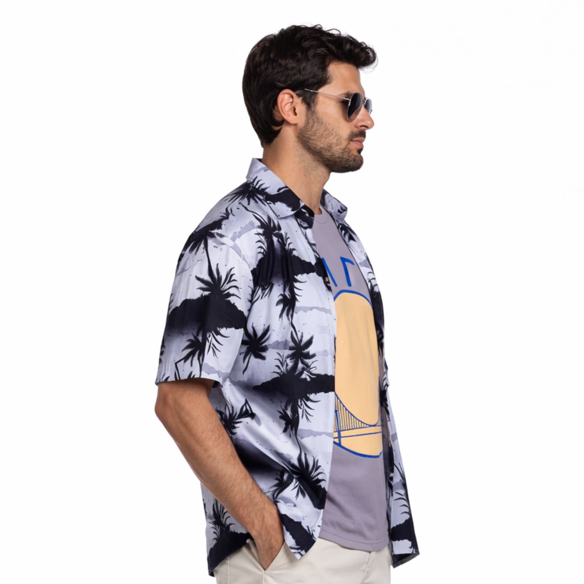 Man wearing a patterned shirt with palm tree design on a white background