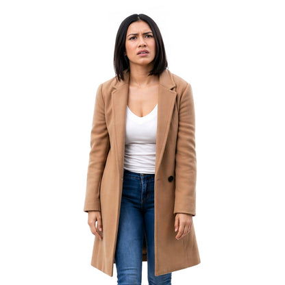 Woman wearing a tan coat over a white shirt and blue jeans on a white background