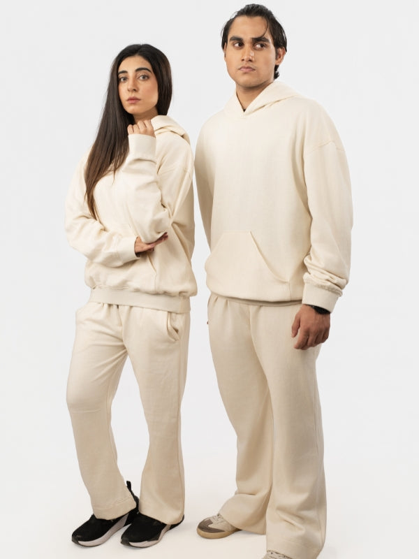 Two people wearing matching beige tracksuits on a white background