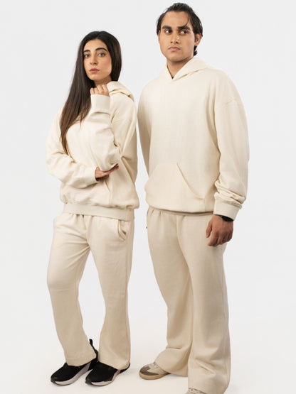Two people wearing matching beige tracksuits on a white background