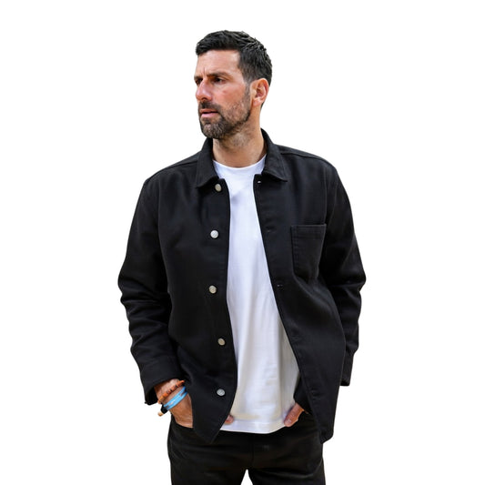 Man wearing a black jacket over a white shirt on a white background