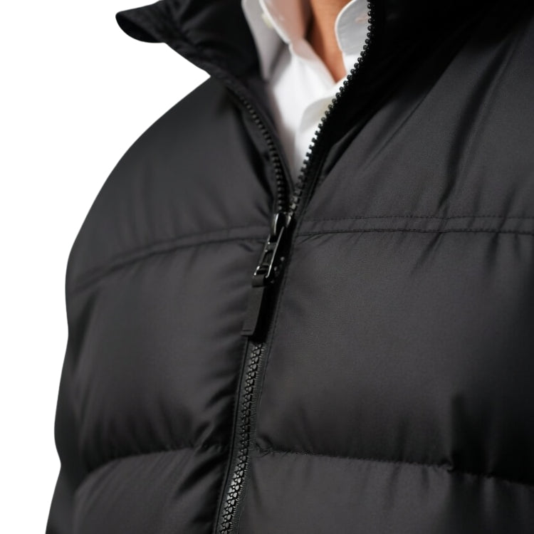 Close-up of a black puffer jacket with a white shirt underneath on a white background