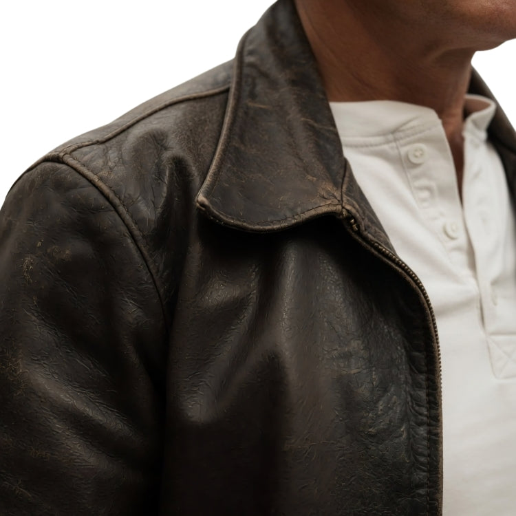 Close-up of a dark leather jacket with a white shirt underneath on a plain background