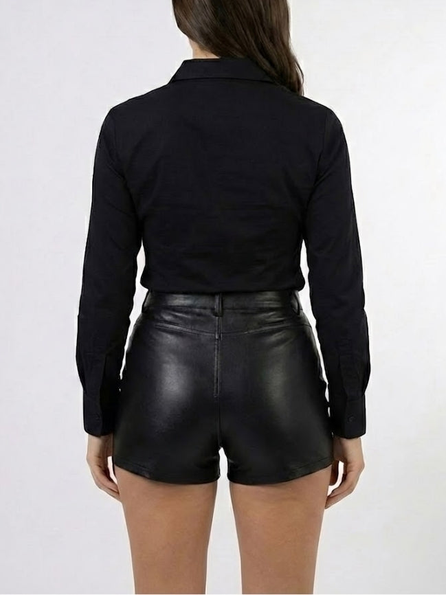 Person wearing a black long-sleeve shirt and black leather shorts on a white background