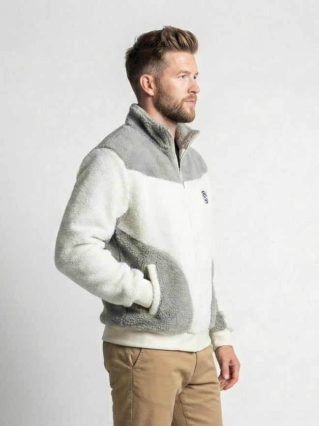 Man wearing a gray and white fleece jacket with a visible brand logo on a light gray background