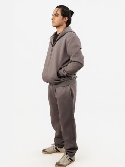 Person wearing a gray tracksuit on a white background