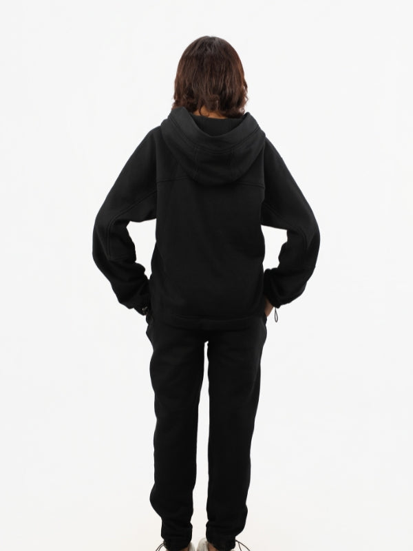 Person wearing a black hoodie and pants on a white background