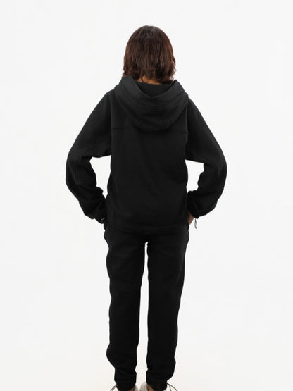 Person wearing a black hoodie and pants on a white background