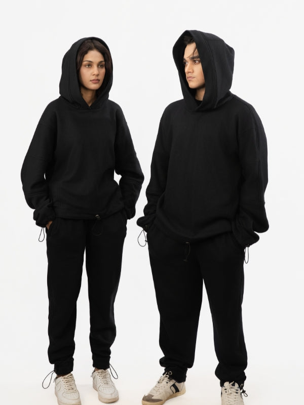 Two people wearing black hoodies and pants on a white background