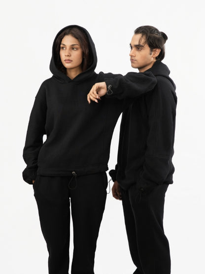 Two people wearing black hoodies and pants on a white background