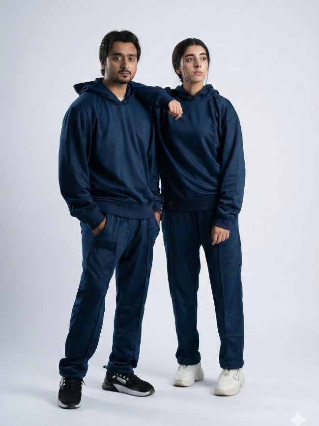 Two people wearing matching navy blue tracksuits on a white background