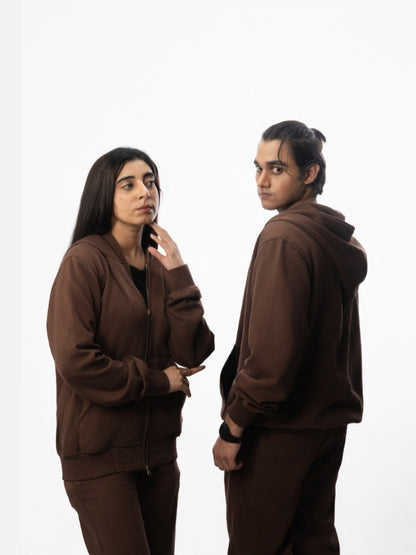 Two people wearing brown tracksuits on a white background