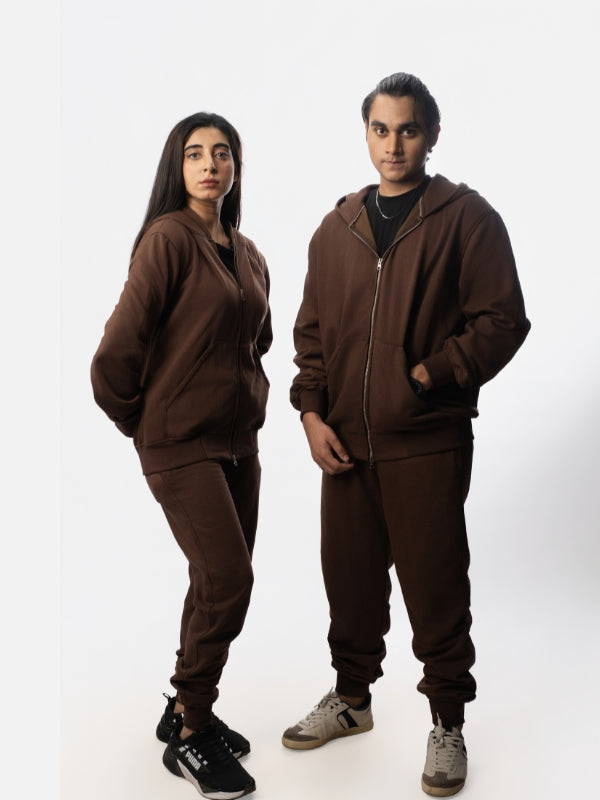 Two people wearing matching brown tracksuits on a white background